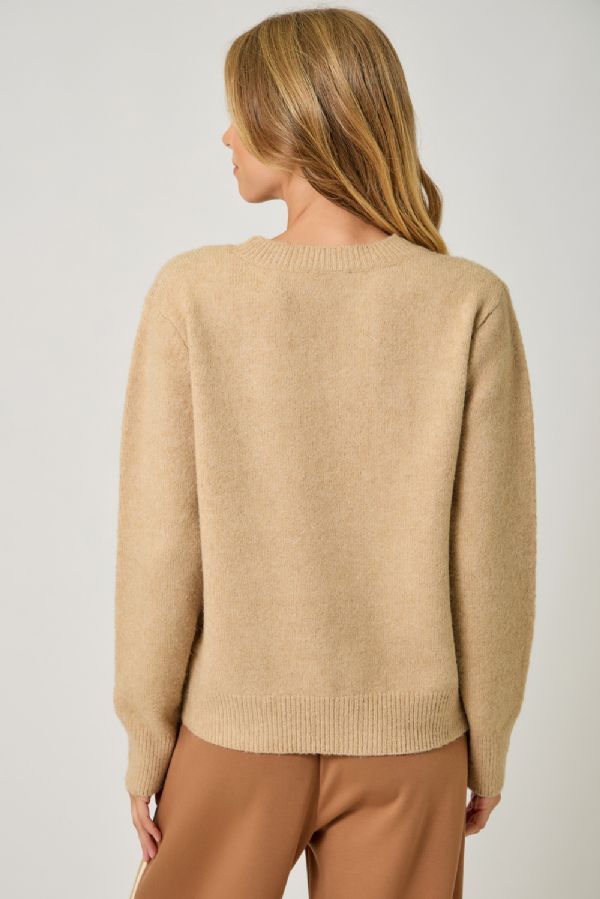 Person wearing a beige sweater that says weekend on it and has a cute llama and brown pants on a plain background