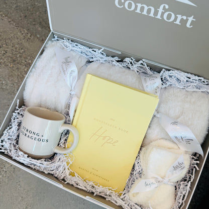 Soft and Cozy Cream Colored blanket and ceramic mug that says strong + courageous. Quotes and Scripture Wordsearch interactive book that says is focused on hope. Paired with a cozy pair of one size fits all socks