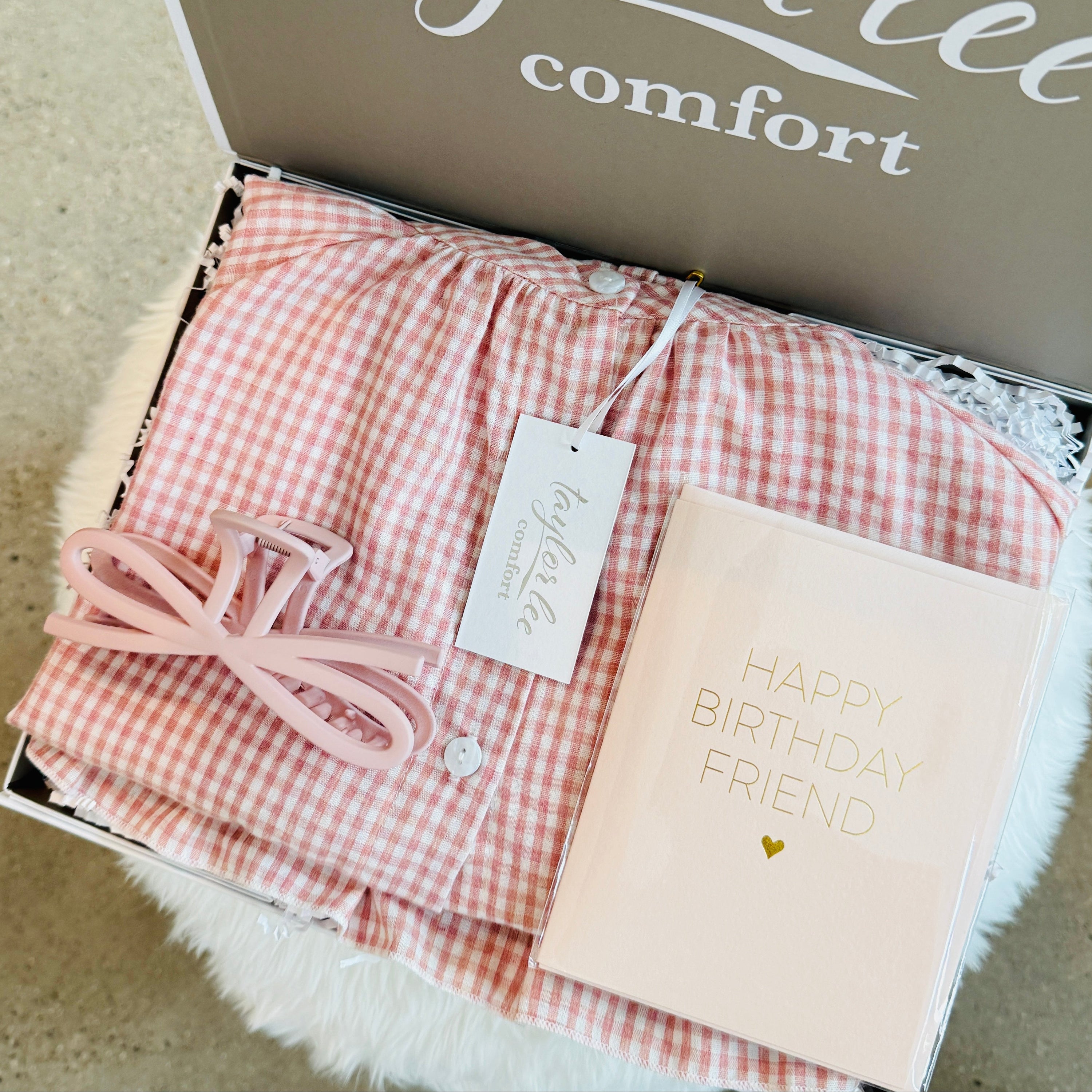 Cute ruffle pink and ivory gingham cotton pajama set, paired with a cute matching hair clip and birthday card that says Happy Birthday Friend. All packaged in a beautiful gift box. 