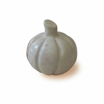 A hand-carved stone pumpkin with natural stone colors including shades of cream, gray, pink, and brown.